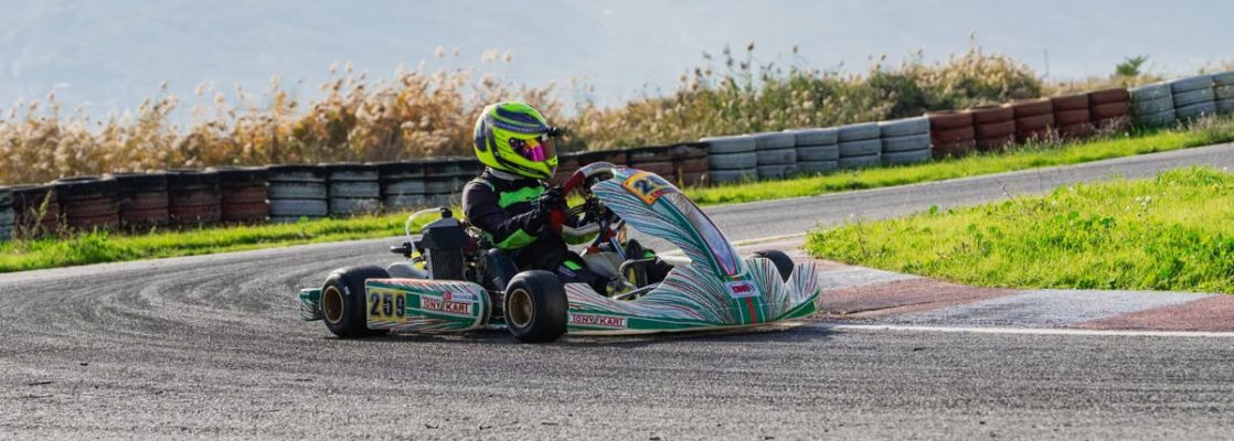 High-speed kart racing on an outdoor track with scenic mountainous background.